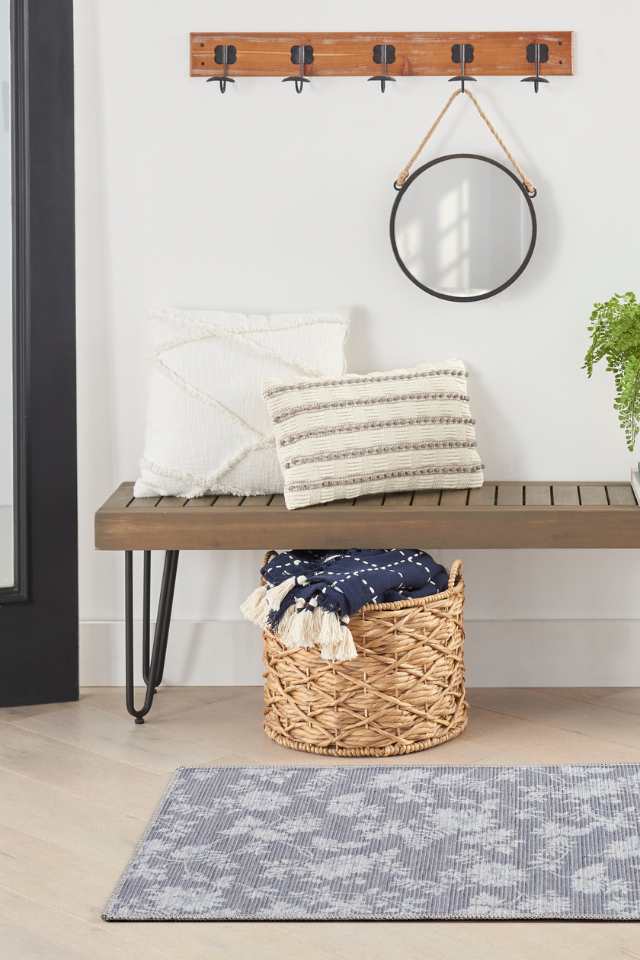 grey area rug in modern entryway with coat rack and wooden bench